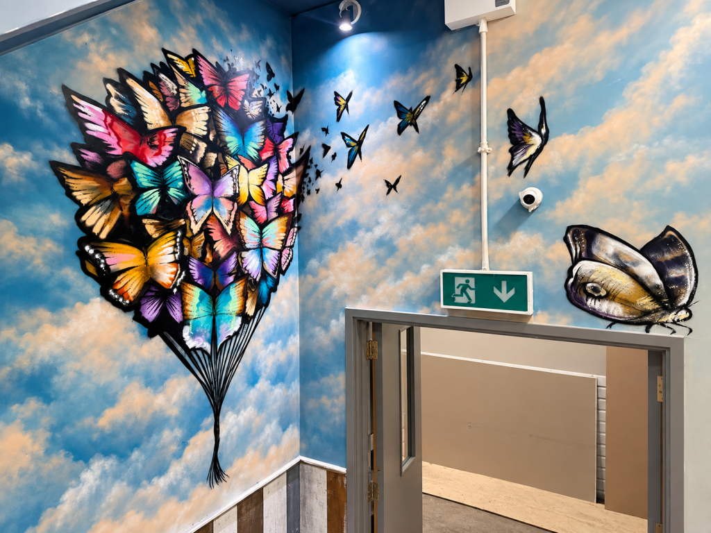 Hand-painted butterfly mural in the stairwell of Claremont Social Tap House Shrewsbury